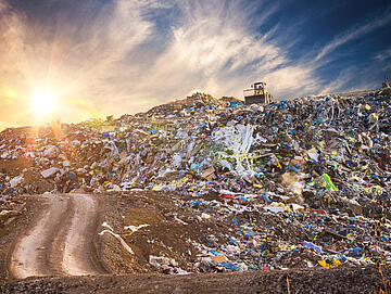 Pollution concept. Garbage pile in trash dump or landfill at sunset.