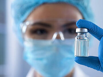 Lady scientist looking at ampoule with new medication, vaccination development